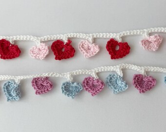 May include: Crocheted heart garland in red, pink, and blue. The hearts are attached to a white crocheted chain. The garland is suitable for Valentine's Day or other romantic occasions.