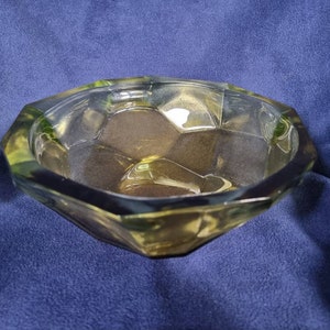May include: A clear glass bowl with a geometric design. The bowl has a light green tint and is made of thick glass.