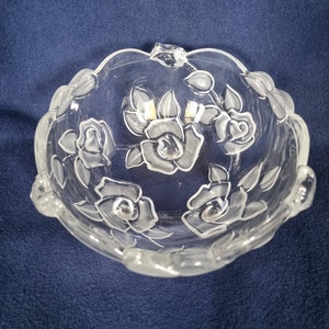 May include: A clear glass bowl with a scalloped rim and etched rose designs. The bowl is ideal for serving snacks or desserts.