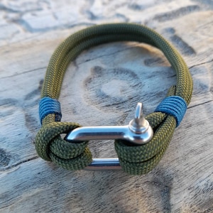 Può includere: Un braccialetto in corda verde e blu con una chiusura in metallo argentato.