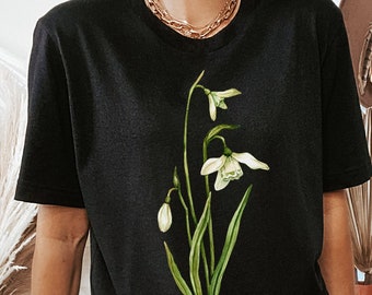May include: Black t-shirt with a white flower graphic print. The flower has green leaves and stems.