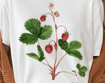 May include: White t-shirt with a watercolor illustration of a strawberry plant with red strawberries and green leaves.