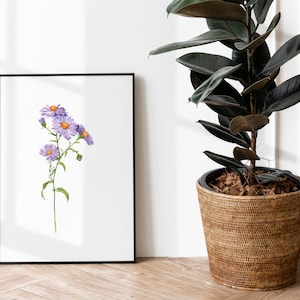 May include: A framed watercolor painting of a purple flower with yellow centers. The painting is hanging on a white wall next to a potted plant.