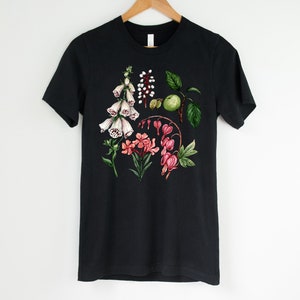 May include: Black t-shirt with a floral print featuring white foxgloves, pink bleeding hearts, and green leaves.