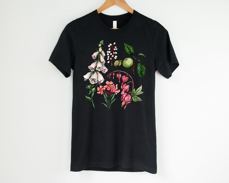 May include: Black t-shirt with a floral print featuring white foxgloves, pink bleeding hearts, and green leaves.