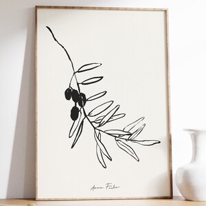 May include: Black and white line art print of an olive branch with olives. The print is signed "Anna Fidler" in the bottom right corner.