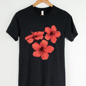 Może przedstawiać: Czarny t-shirt z nadrukiem trzech czerwonych kwiat&oacute;w hibiskusa.