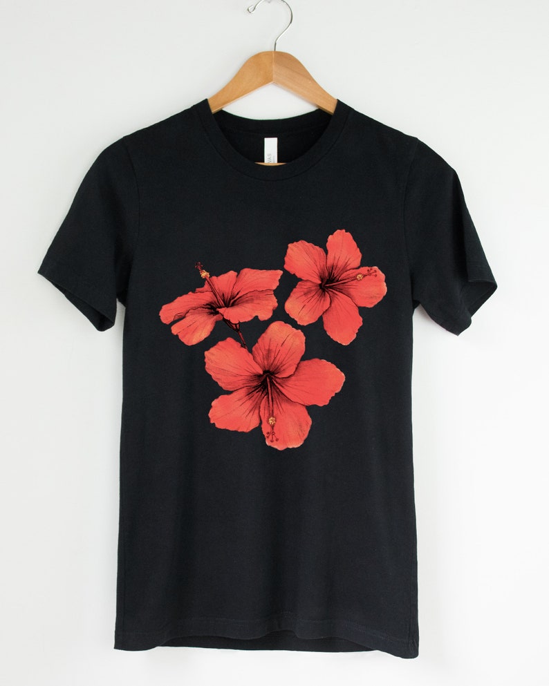 Może przedstawiać: Czarny t-shirt z nadrukiem trzech czerwonych kwiat&oacute;w hibiskusa.