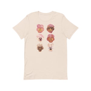 May include: A cream-colored t-shirt with a pattern of six pink and orange pansies.