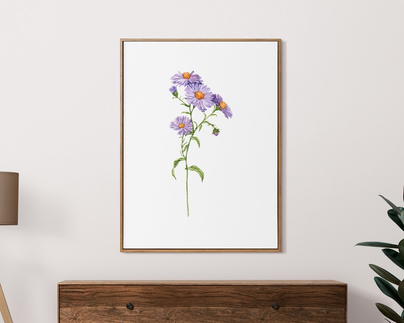 May include: A framed watercolor painting of a single stem of purple wildflowers with yellow centers. The flowers are in bloom and the stem is green. The background is white.