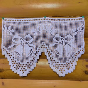 May include: White crocheted valance with a scalloped edge and a floral design. The valance is made of delicate crochet lace and has a classic, vintage look.