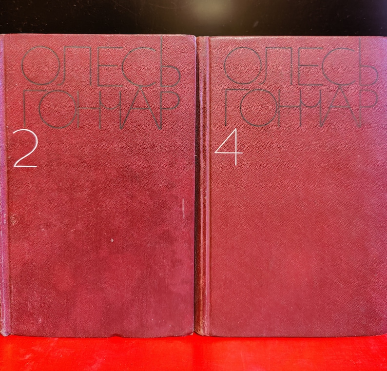 Puede incluir: Dos libros encuadernados en color burdeos con el texto "ОЛЕСЬ ГОНЧАР" y los n&uacute;meros "2" y "4" en los lomos.