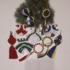 Op de afbeelding: Een verzameling handgemaakte kerstversieringen met verschillende kleuren en patronen. De versieringen zijn gemaakt van garen en omvatten verschillende vormen, waaronder cirkels, sterren en sneeuwvlokken.