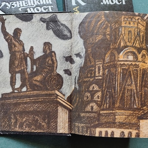 May include: An open book with a brown and white illustration of a statue of two figures standing on a pedestal. The background of the illustration is a light gray with black birds flying. The book is open to a page with a brown and white illustration of a building with a large window. The book cover has the Russian text 'Кузнецкий Мост' which translates to 'Kuznetsky Most'.