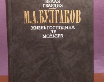 Könnte beinhalten: Ein schwarzes Buch mit goldenen Lettern auf dem Einband. Der Titel lautet "Die Weiße Garde" von M.A. Bulgakov. Der Untertitel lautet "Das Leben des Herrn de Molière."