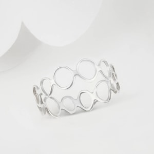 May include: A silver ring with a unique design featuring multiple interconnected circles.