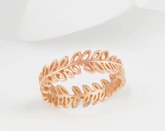 May include: A rose gold ring with a delicate leaf design. The ring is made of a thin band with a repeating pattern of leaves.