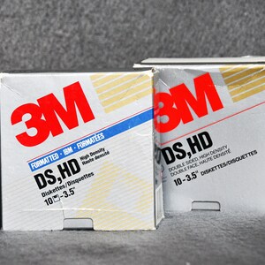 以下が含まれることがあります： 3M DS,HD 3.5インチ ディスク 2パック。パックはシルバーとホワイトで、ゴールドとブルーのアクセントが施されています。パックのテキストには、「FORMATTED IBM FORMATÉES DS,HD High Density Haute densité Diskettes/Disquettes 10-3.5」と「DS,HD DOUBLE SIDED, HIGH DENSITY DOUBLE FACE, HAUTE DENSITE 10-3.5」 DISKETTES/DISQUETTES と書かれています。