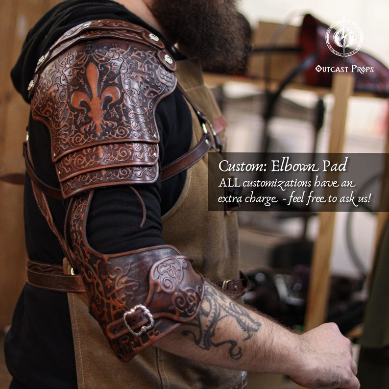 May include: A brown leather elbow pad with detailed embossed floral and fleur-de-lis patterns. The armour has multiple articulated plates and is fastened with buckles and straps. The text "Custom: Elbow Pad" is visible.