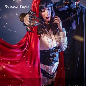 Little Red Riding Hood and the Wolf. Sexy pic. Fantasy couple in dramatic lighting showing the previous black model of the witch leather corset. The new version features nickel hardware and refined buckles. Ideal for gothic, LARP, and steampunk events. The waist cincher enhances the silhouette with historical elegance and fantasy charm, handcrafted from premium vegetable-tanned leather for ren faire and witch costume ensembles.
