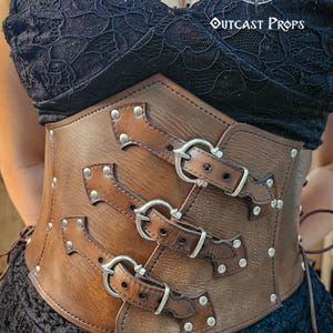 Close-up of the aged brown witch leather corset with nickel buckles, handcrafted from premium vegetable-tanned leather. The structured shape enhances the waistline, ideal for steampunk waist cincher, gothic clothing, or ren faire outfit. Each strap is riveted for strength, and the hidden clasp insert locks the front panel securely. Designed for witches and alchemists seeking cinematic authenticity at LARP or fantasy festivals.