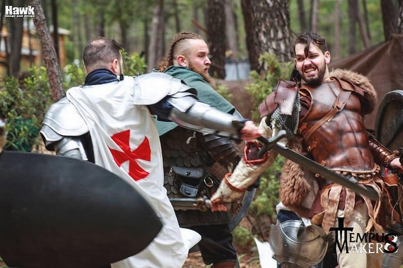 Live-action LARP battle photo featuring a warrior wearing the brown Roman leather musculata while clashing swords with a templar. The armor is paired with fur and tattered gear, ideal for barbarian or gladiator cosplay. This immersive shot highlights the armor in motion, showcasing its comfort, durability, and visual impact during roleplay combat scenes.