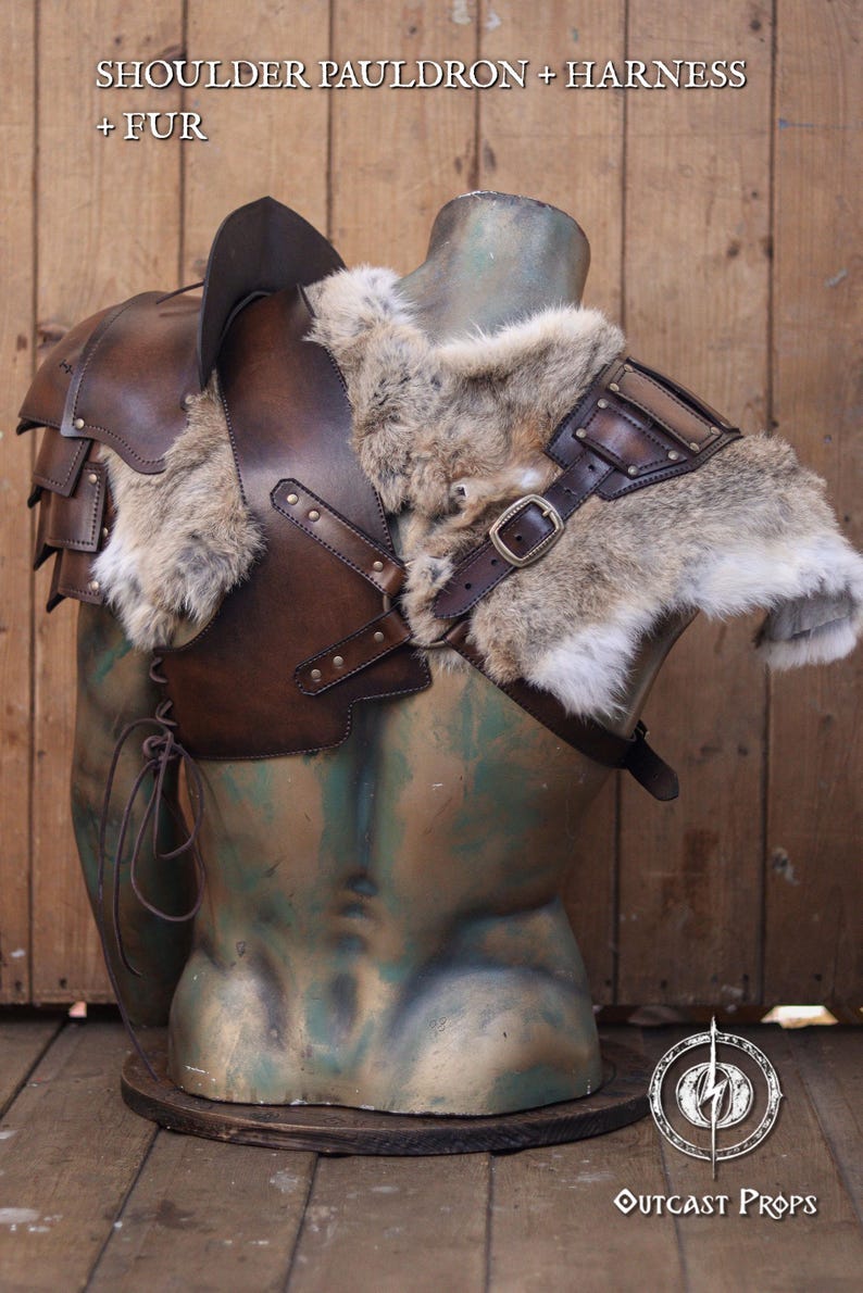 Mannequin bust wearing full barbarian leather shoulder armor set with crossed harness and riveted pauldrons. The armor is aged brown, handcrafted in vegetable-tanned leather with visible patina and hand-stitched details. Worn over a dark medieval shirt, this larp armor set includes sword scabbard on the back. Perfect for viking costume, post-apocalyptic larp, or warrior cosplay outfit.