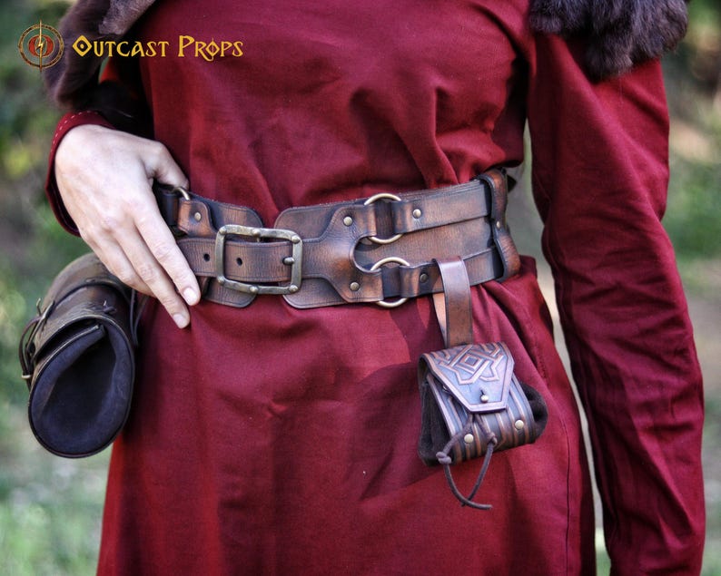 Leather coin pouch worn on a belt alongside other fantasy leather accessories. Small embossed pouch with geometric Celtic patterns, handcrafted from vegetable-tanned leather and finished with artisanal aging. Designed to carry coins, dice, or small valuables. Suitable for Viking, Celtic, dwarven, or medieval-inspired outfits, LARP, cosplay, Renaissance fairs, or fantasy-themed everyday wear.