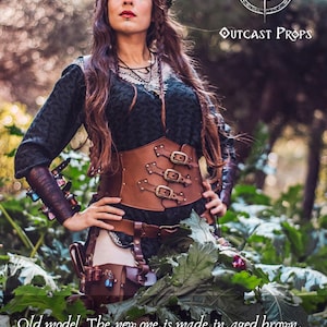 Female LARP witch wearing the old version of the leather underbust corset by Outcast Props. The updated design is made in aged brown leather with nickel hardware and more elegant buckles. Perfect for ren faire outfits, fantasy costumes, and steampunk waist cincher looks. Handcrafted from vegetable-tanned leather, this corset embodies artisanal craftsmanship for witches and alchemists.