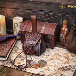 Handcrafted leather coin pouch on an old fantasy map with metal coins in front. Made from premium vegetable tanned leather with embossed geometric patterns and an aged brown finish. Small medieval belt pouch for coins, dice, keys, small jewelry, or a compact tobacco pouch. Ideal for Celtic, Viking, dwarf, fantasy, LARP, Renaissance fair, cosplay, or as a unique handmade leather gift.