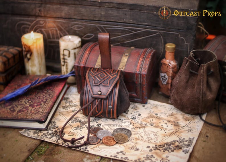 Handcrafted leather coin pouch on an old fantasy map with metal coins in front. Made from premium vegetable tanned leather with embossed geometric patterns and an aged brown finish. Small medieval belt pouch for coins, dice, keys, small jewelry, or a compact tobacco pouch. Ideal for Celtic, Viking, dwarf, fantasy, LARP, Renaissance fair, cosplay, or as a unique handmade leather gift.