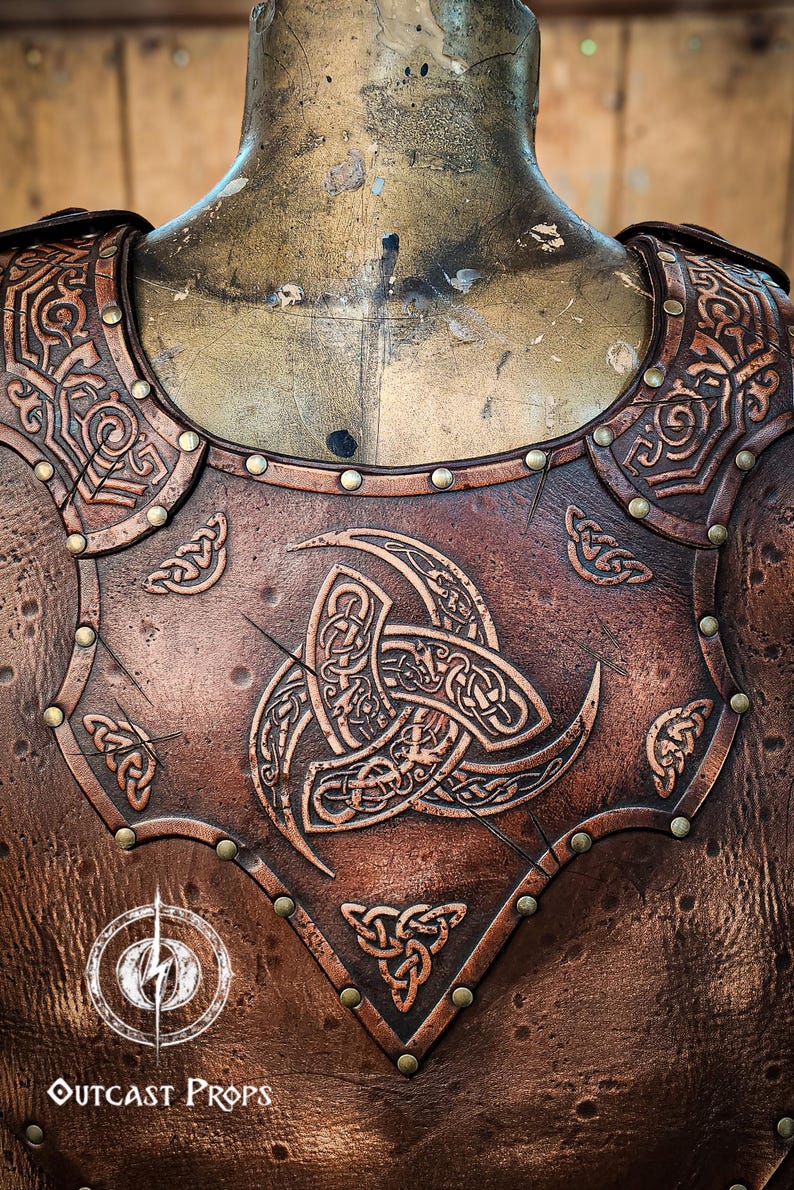 May include: A brown leather chest piece with intricate Celtic knotwork designs and brass rivets. The chest piece features a large, central knotwork design with three points.