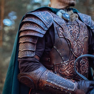 May include: A person wearing a leather armor with intricate carvings and a blue face paint. The armor is made of brown leather and has a Celtic knot design. The person is wearing a green cloak and is holding a sword.