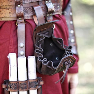 Open leather coin pouch hanging from a belt, showing the interior capacity. Small handcrafted pouch made from vegetable-tanned leather with embossed Celtic-style patterns and suede lining. Ideal for carrying coins, dice for tabletop games, or small daily items. A versatile leather accessory for Viking, Celtic, medieval, or dwarven aesthetics, suitable for LARP, cosplay, Renaissance fairs, or fantasy events. Leather coin pouch with Celtic or Viking embossing