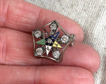 May include: A silver Masonic pin with a five-pointed star design. The star is surrounded by rhinestones and features a colorful enamel design with Masonic symbols.