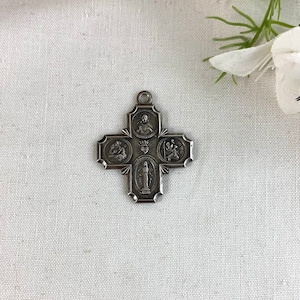 May include: Silver-toned metal pendant in the shape of a cross with five medallions depicting religious figures. The center medallion features the Virgin Mary.