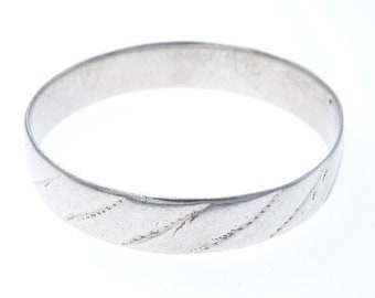 May include: A silver band ring with a textured design. The ring is plain and has no gemstones.