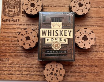 May include: A wooden game board with the text "Whiskey Poker" and instructions for playing the game. The board includes wooden chips with different card suits and a deck of playing cards with the text "Whiskey Poker Premium Playing Cards".