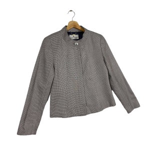 Puede incluir: Una chaqueta de color negro y blanco con estampado de pata de gallo, con un solo bot&oacute;n de cierre y un cuello alto.
