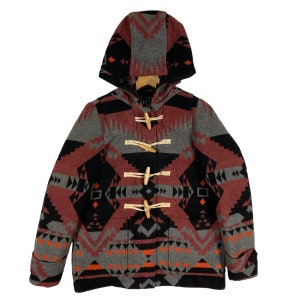 Puede incluir: Un abrigo de lana con capucha rojo, negro y gris con un patrón geométrico. El abrigo tiene un cierre de botones y una capucha.