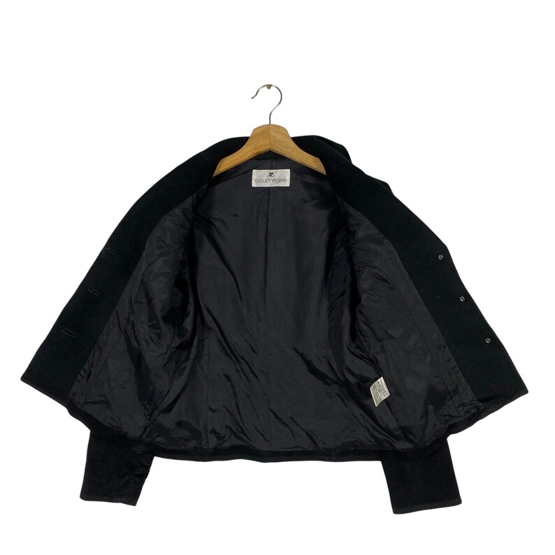 May include: A black wool blazer with a button closure and long sleeves. The blazer has a label that reads "Courreges" inside.