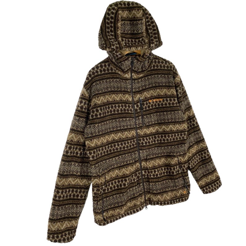 Puede incluir: Una chaqueta de forro polar con estampado marr&oacute;n y beige, con cierre de cremallera y capucha. La chaqueta tiene un patr&oacute;n geom&eacute;trico.
