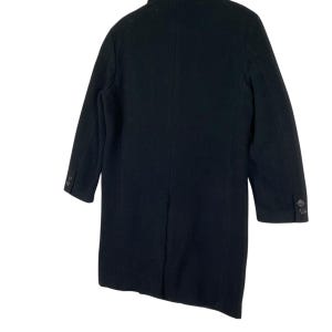 Pu&ograve; includere: Un cappotto nero dal design classico. Il cappotto presenta una chiusura con bottoni e due bottoni su ogni manica. Il cappotto &egrave; realizzato in un materiale scuro e tinta unita e ha una vestibilit&agrave; sartoriale. Adatto al freddo.