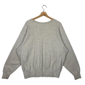 May include: A heather grey sweatshirt with long sleeves and a crew neck.