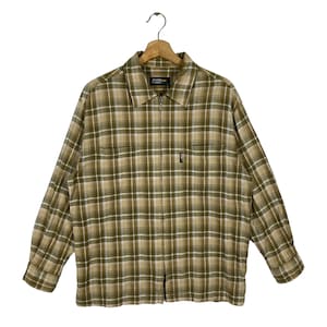 May include: A brown and beige plaid long-sleeved shirt with a zipper closure. The shirt has a  "Brother Forest" label on the left side of the collar.
