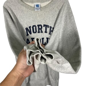 May include: Gray sweatshirt with a navy blue "NORTH CAROLINA" logo.