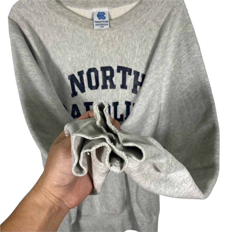 May include: Gray sweatshirt with a navy blue "NORTH CAROLINA" logo.