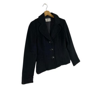 May include: A black blazer with a notched collar, three buttons, and long sleeves. The blazer is made of a soft, textured fabric. The label on the blazer reads "Coldwater Creek".