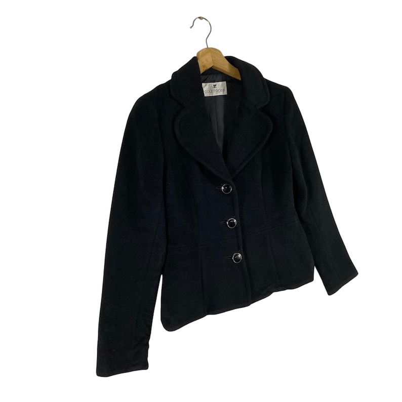 May include: A black blazer with a notched collar, three buttons, and long sleeves. The blazer is made of a soft, textured fabric. The label on the blazer reads "Coldwater Creek".