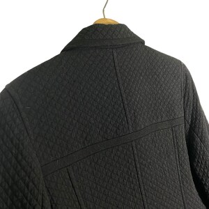 Puede incluir: Chaqueta acolchada negra con cuello y una costura en la espalda.